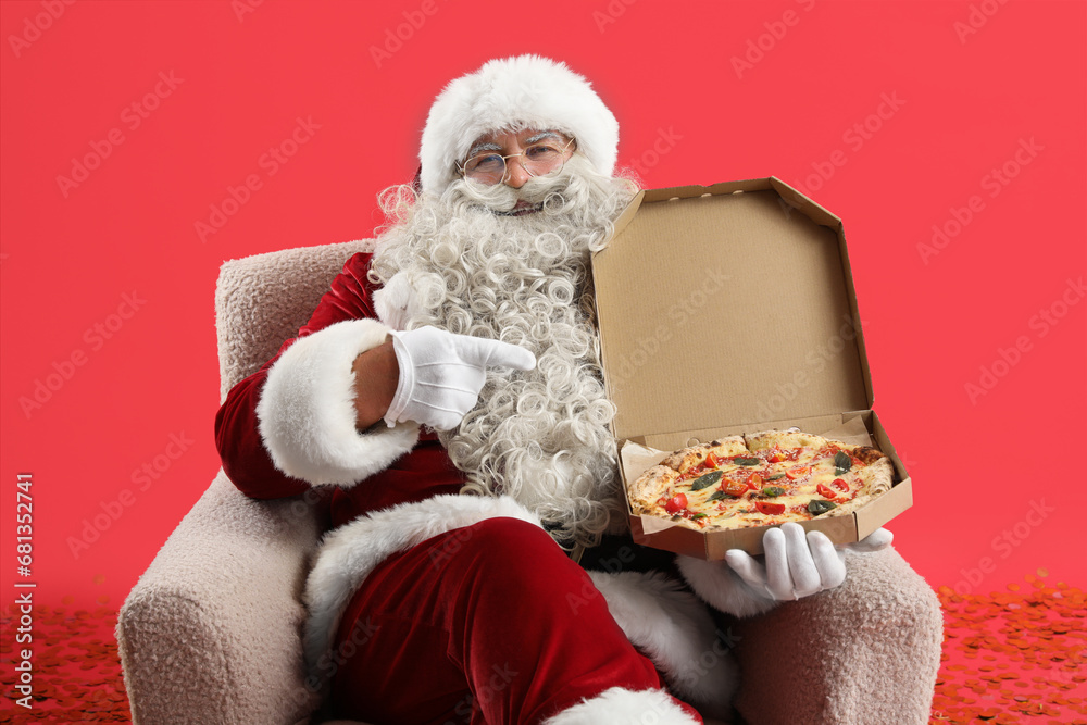 Santa Claus pointing at box with tasty pizza on red background