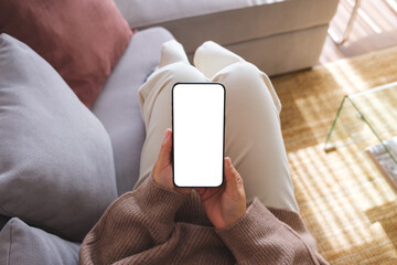Wall Mural - top view mockup image of a woman holding mobile phone with blank desktop white screen while lying on