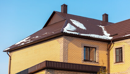 Wall Mural - Roof of a house covered in snow against a blue sky