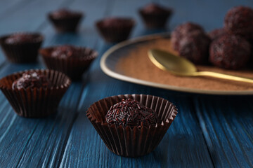 Wall Mural - Brigadeiro and plate with golden spoon on blue wooden background, close up