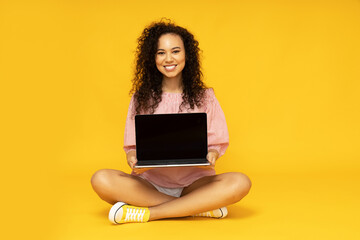 Wall Mural - Young attractive girl with a laptop on a yellow background