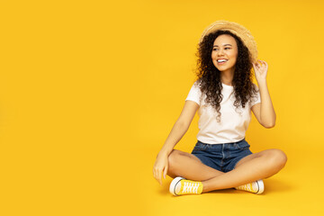 Wall Mural - Young attractive girl in a hat on a yellow background