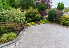 Stylish block paving drive with beautiful garden border with shrubs and flowers.