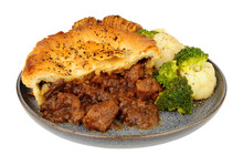 Steak pie with rich all butter puff pastry meal with hasselback potatoes, broccoli and cauliflower isolated on a white background