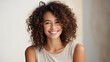 Portrait of beautiful young woman with curly hair smiling at camera.