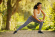 Sportswoman with earbuds exercising doing deep side lunge stretching outdoors