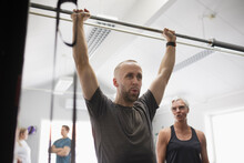Mid Adult Man Lifting Barbell Pole In Gym