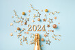 2024 golden champagne bottle christmas and New Year composition with party streamers, confetti stars and holiday decorations. Flat lay and top view.