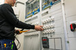 © Johnér - Midsection of repairman with voltage tester repairing switchboard in industry