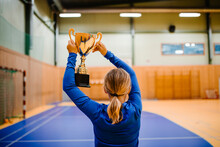 Rear View Of Girl Holding Golden Trophy While Standing In Sports Court