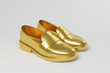 Golden chunky loafer shoes floating in mid air with shadow on white background in monochrome. Illustration of the concept of footwear, menswear and fashion