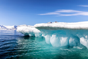 Wall Mural - Glacial blue iceberg and sky background. Underside of a snow covered iceberg in Svalbard, a Norwegian archipelago between mainland Norway and the North Pole