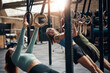 © Flamingo Images - Young women working out together on rings during a gym class