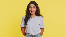 Funny Comical Playful Indian Young Woman Making Silly Facial Expressions Grimacing Fooling Around, Showing Tongue, Idiotic Expression. Comedian Arabian Girl On Yellow Background. People Lifestyles