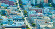 Sunny San Francisco neighborhood with residential housing and street splitting up the rows, CA