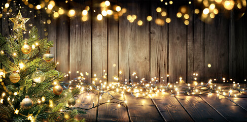 Wall Mural - christmas - defocused string light on rustic wooden table with christmas tree
