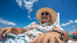 Happy man in straw hat and sunglasses sitting on sunbed on the beach