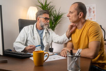 Wall Mural - Friendly middle-aged man doctor checking sore throat or thyroid glands