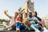 Fototapeta Londyn - Multiracial group of happy young friends bonding in London city - Multiethnic teens students meeting and having fun in Tower Bridge area, UK - Concepts about youth lifestyle, travel and tourism