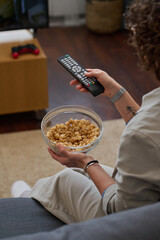 Wall Mural - Vertical image of woman watching TV with popcorn at home