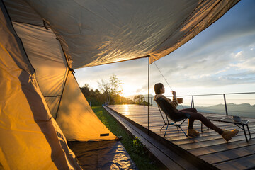 Canvas Print - Woman go camping and sit outside with the snack under sunset