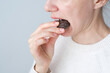 Close up an unrecognizable person biting a chocolate. Unhealthy eating. Dental health concept. High quality photo