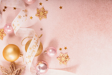 Wall Mural - Festive Christmas and New Year background with gold and pink baubles, ribbons and stars. White ribbon with Merry Christmas written. Flat lay, top view with copy space