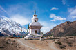 A spiritual monument stands proudly under the clear blue sky, flanked by the majestic Himalayas and prayer flags