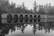 Historic stone bridge in black and white reflecting in lake in Cumberland Mountain State Park