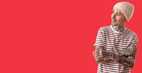 Wall Mural - Tattooed young man on red background with space for text