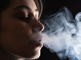 Wall Mural - Brunette latin woman smoking face closeup isolated on studio black background