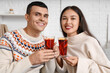 Happy couple with glasses of warm mulled wine in living room, closeup