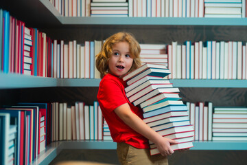 Fototapete - Surprised pupil. School boy reading book in library. Kids development, learn to read. Pupil reading books in a book store.