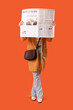 Young woman with newspaper on orange background