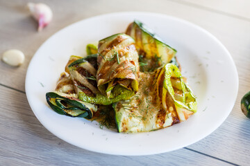 Wall Mural - Grilled zucchini pieces with garlic sauce in a white plate.