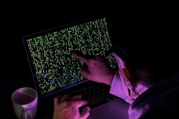 hacker on laptop computer with binary code