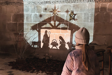 Wall Mural - A child looks at christmas creche with Joseph Mary and small Jesus in a crib