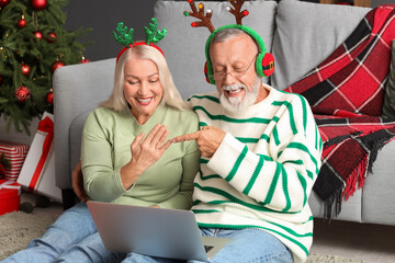 Canvas Print - Engaged mature couple with laptop video chatting at home on Christmas eve