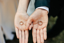 The Bride And Groom Hold Wedding Rings In Their Hands