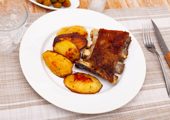 Wall Mural - Delicious barbecued pork spare ribs served with baked potatoes on plate