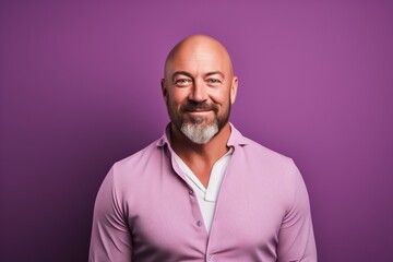 Wall Mural - Portrait of a happy mature man smiling at camera against purple background