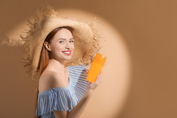 Poster - Beautiful young woman in sunlight holding sun protection cream on beige background, space for text