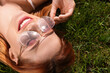 Beautiful woman in sunglasses on green grass outdoors, space for text