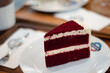 A red velvet cake is placed on a white ceramic plate.