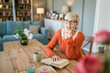 © Miljan Živković - Senior woman mature caucasian female read book at home wear eyeglasses