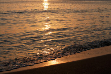 Wall Mural - Reflection of sunlight on calm sea water and sand at sunset