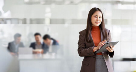 Elegant businesswoman standing in office with digital tablet