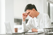 © R Photography - Asian male people concerned person in white shirt looks at laptop, possibly stressed, hand on their forehead. middle age businessman