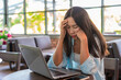 © Kittiphan - Tired and stressed young Asian woman working with laptop sitting at working space