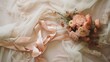  a bouquet of flowers sitting on top of a bed next to a sheer pink scarf on top of a white comforter with lace on the bottom of the sheets.